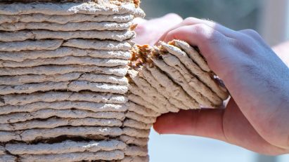 Hands peeling a column of 3D printed sawdust