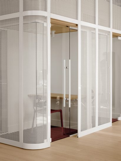 Glass-walled phone booth behind steel mesh