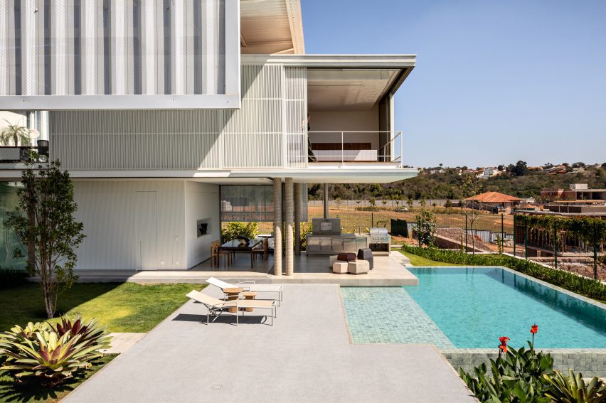 A contemporary home overhanging a pool and large patio