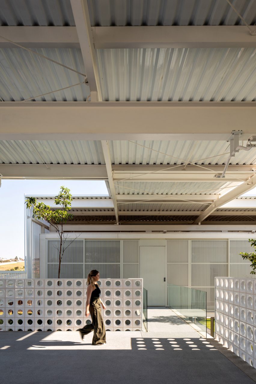 A person walking underneath the corrugated metal ceiling of a residence in Brazil