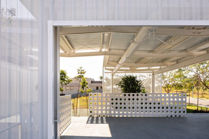 An porch with a flat metal roof and a perforated white fence