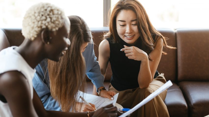 Three women sat together taking notes