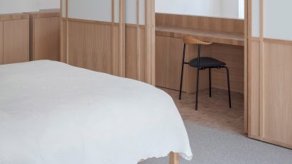 Chair at a wooden desk in a study area separated from a bedroom with sliding doors