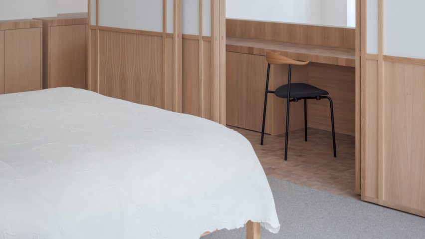 Chair at a wooden desk in a study area separated from a bedroom with sliding doors