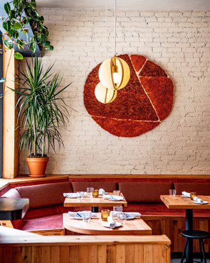Banquette seating with wool wall hanging above in Donna restaurant