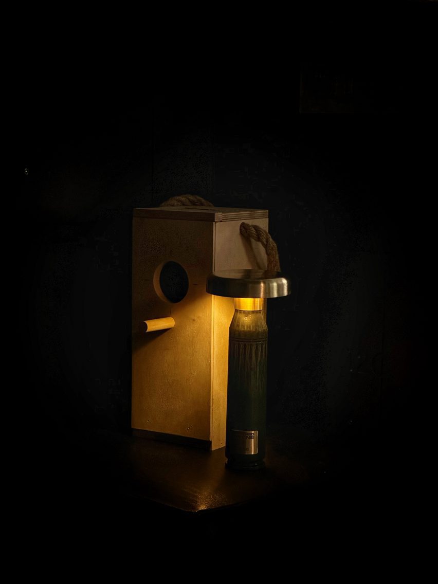 Dark green lamp in darkness beside wooden bird box