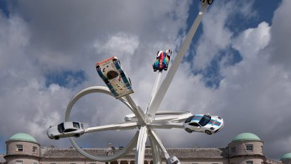 White steel sculpture with cars attached