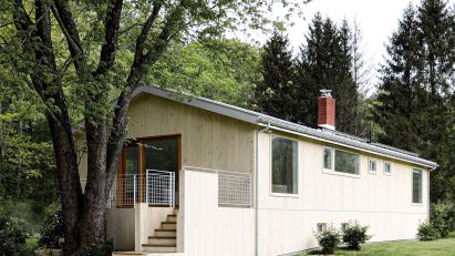 Wood-clad ranch house in New York with steps leading to a deck