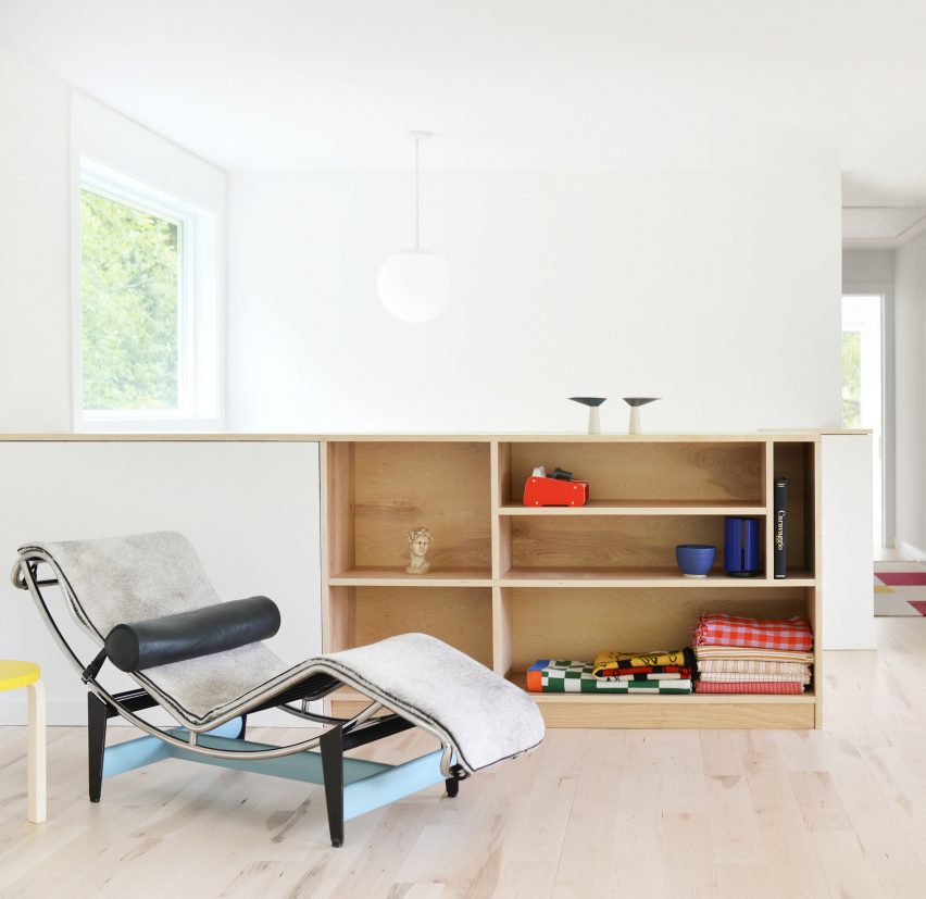 A room with white walls, wood flooring and built-in wooden storage