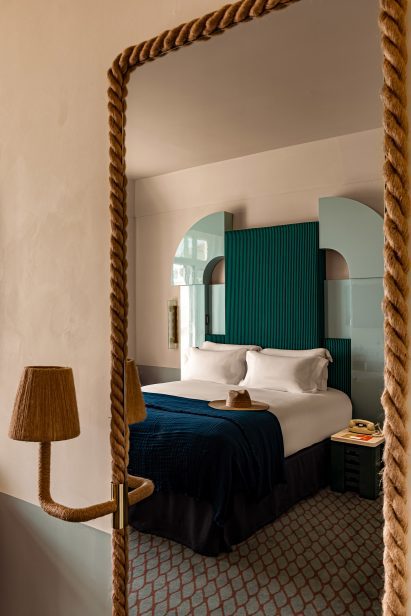 Reflection of a bed in a rope-wrapped mirror
