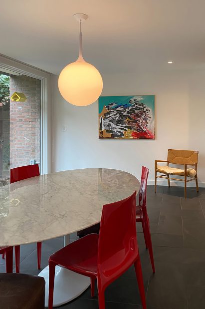 Interior of townhouse with globe pendant light and red chairs