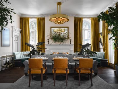Dining space with mismatched furniture and tall ochre curtains