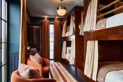 Room with four wooden bunk beds and two armchairs