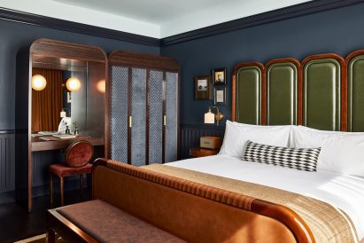 Guest room with dark blue walls and green leather headboard