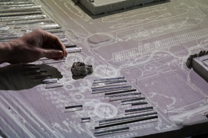 Collection of small model figures on top of a projection of a drawing
