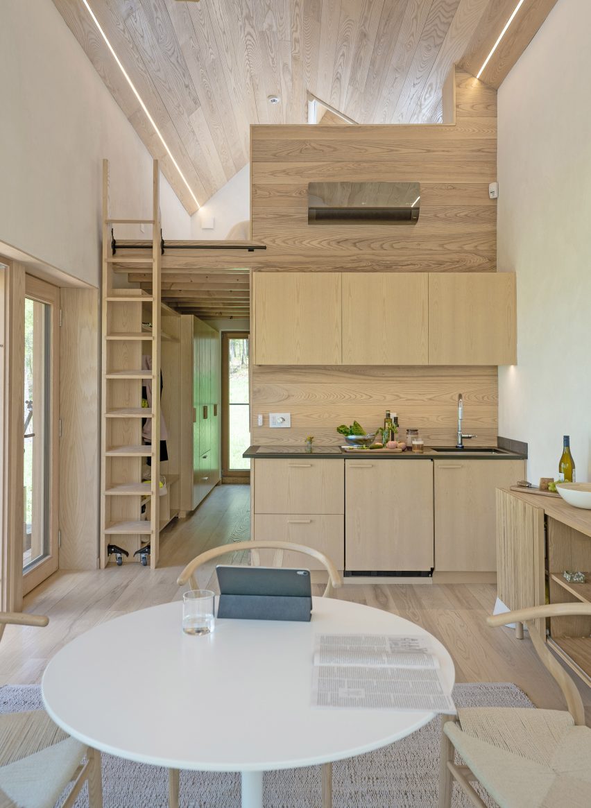 A small kitchen with light wood cabinets and a loft