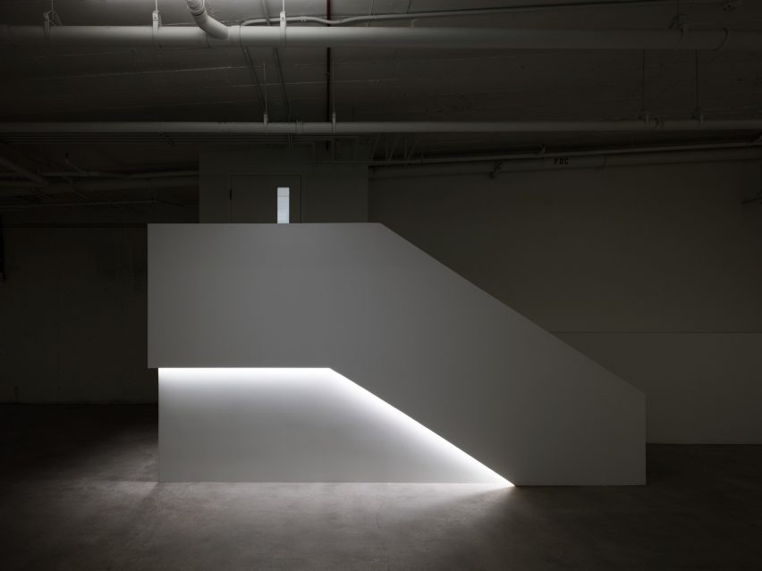 The blocky, white staircase with strip lighting that leads into a dark basement