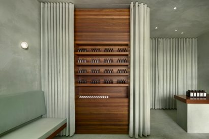 Walnut shelving behind green velvet curtains