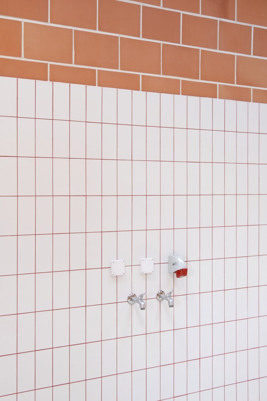 Water taps on a white-tile and terracotta brick wall