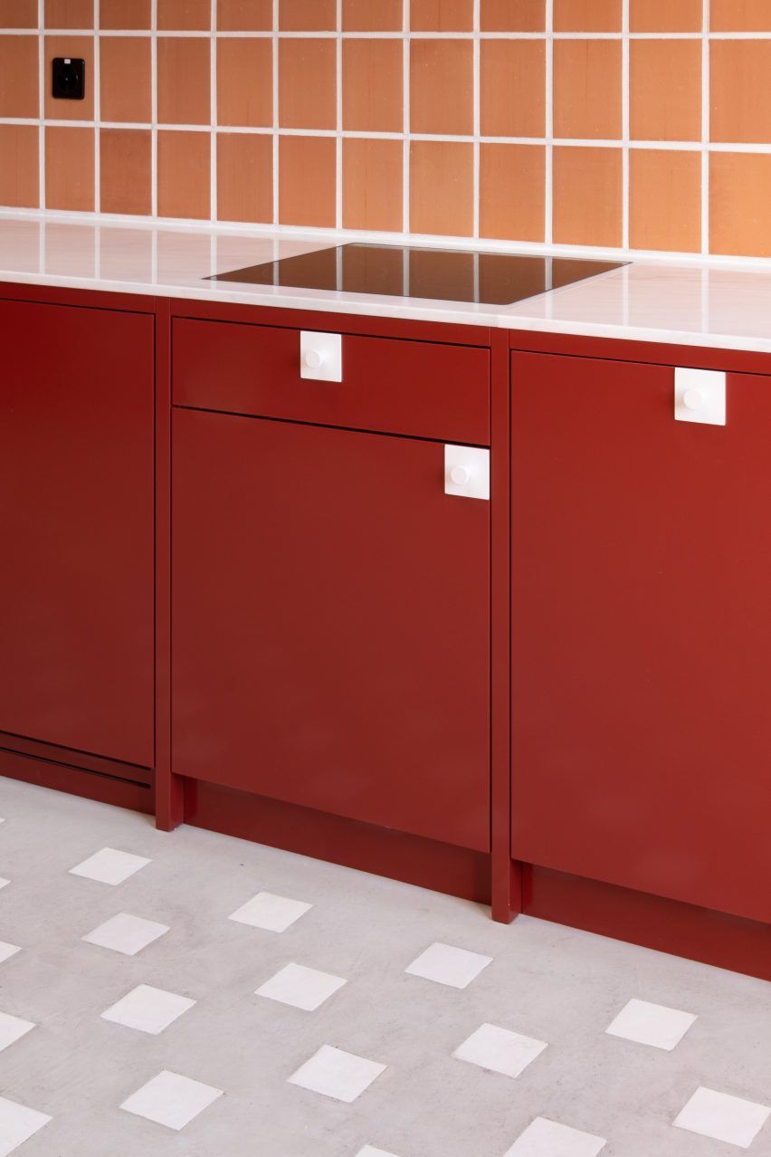 Red kitchen units with terracotta wall tiles
