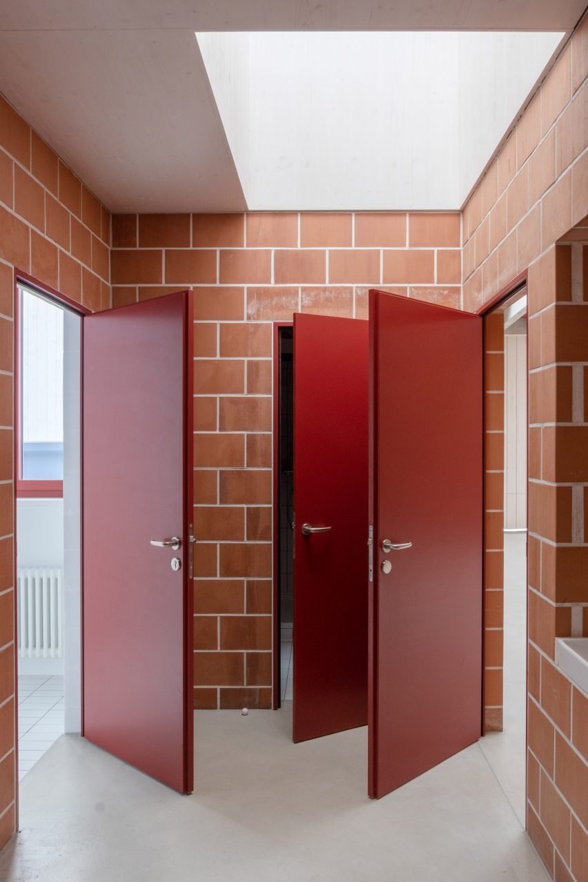 Three red doors open in a terracotta brick entryway