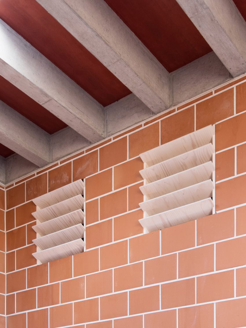 Air vents on a terracotta brick wall with concrete roof beams