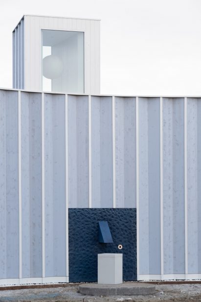 Pleated blue-timber structure with a roof lantern and blue water fountain