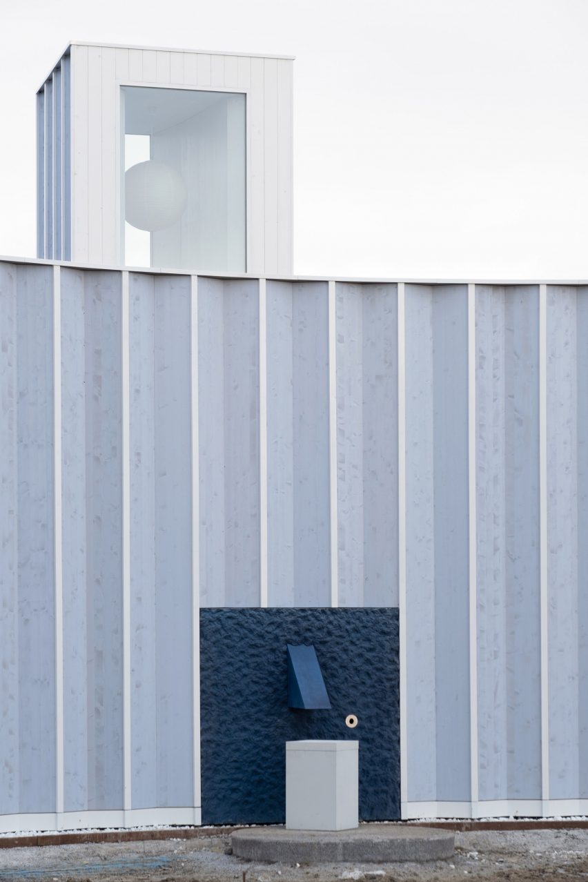 Pleated blue timber structure with a roof lantern and blue water fountain