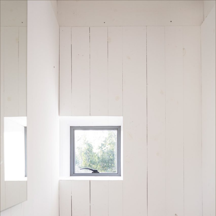 A small window in a wall clad with wooden panels