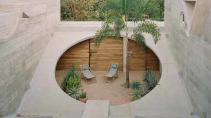 A home with two large cutouts in the center with plants inside