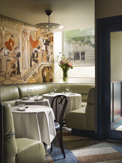 Dining area with pistachio banquettes and wall mural