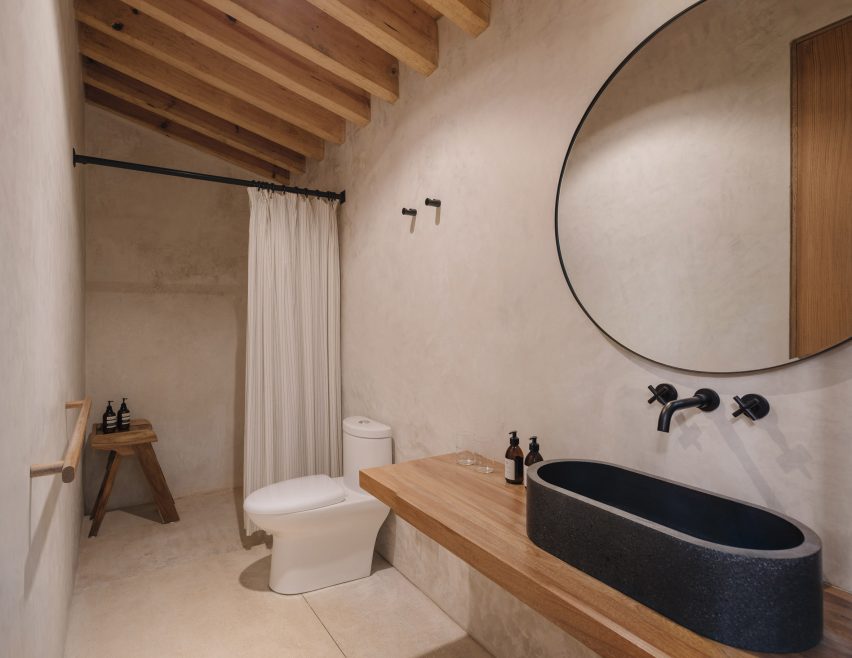 Bathroom with white walls, timber roof beams, a black oval sink and a walk-in shower