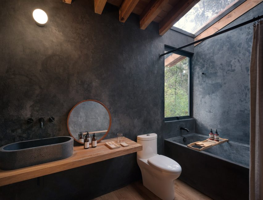Bathroom with black textured walls and timber roof beams