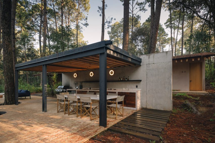 Outdoor kitchen with a black timber roof canopy by Estudio Atemporal