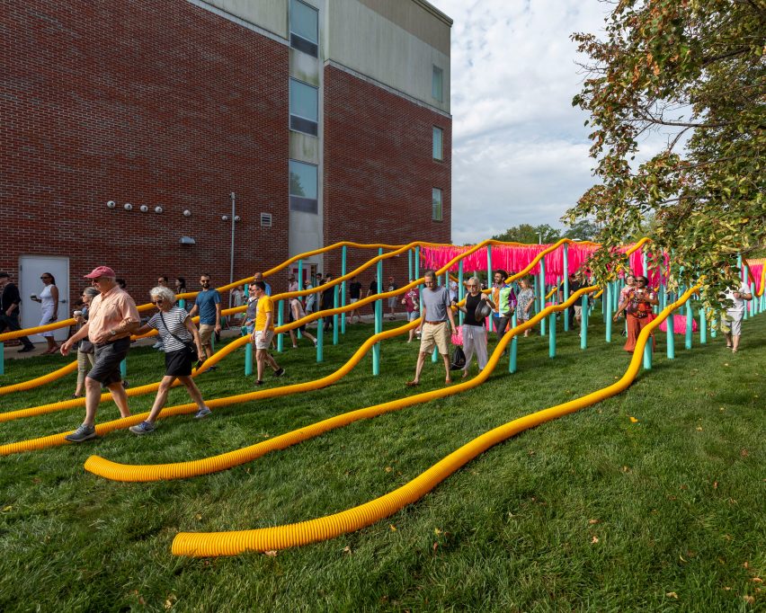 An installation with undulating plastic tubing held up by blue poles