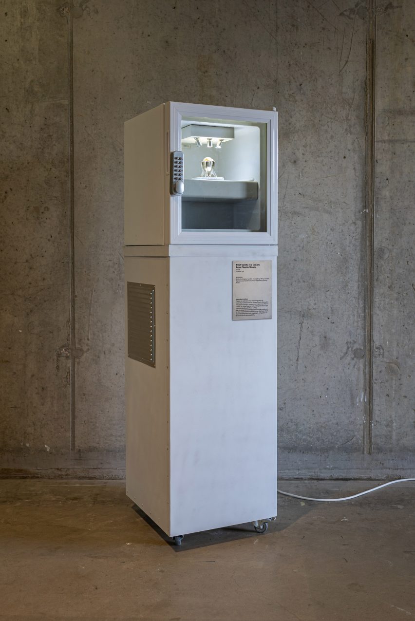 Photograph of a tall white fridge with a keypad lock on the door and a window showing a single cup of ice-cream inside