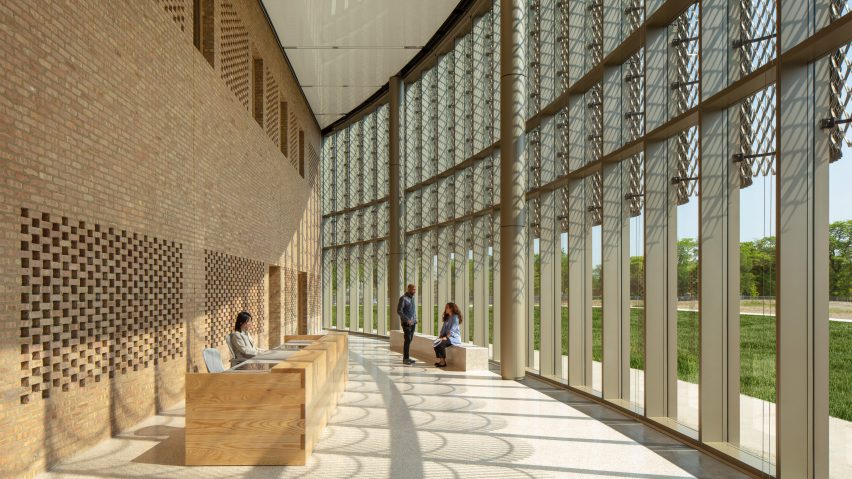Curved circulation space with brick walls on one side and a glass facade