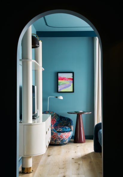 View through an arched opening into a blue bedroom