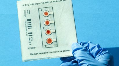 Blue gloved hand holding test sample