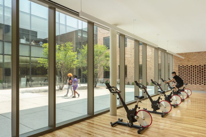 indoor gym with bike machines next to windows overlooking a courtyard