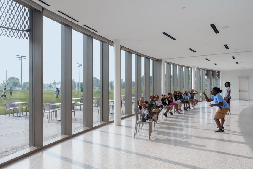 Children sitting in a white interior with a glass facade