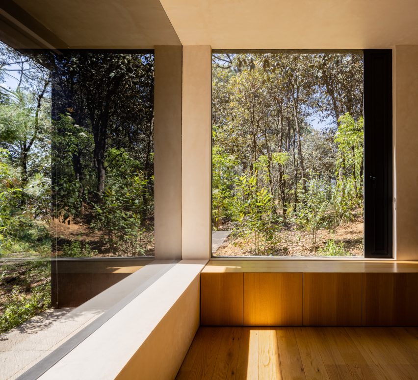 Large windows in a corner of a room that looks out at a forest