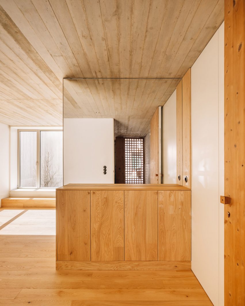 Interior with wood flooring and built-in furniture, white walls and exposed board-formed concrete ceiling