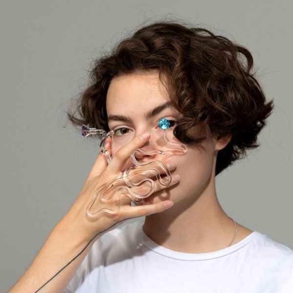 Person holding a piece of glass jewellery in front of their face
