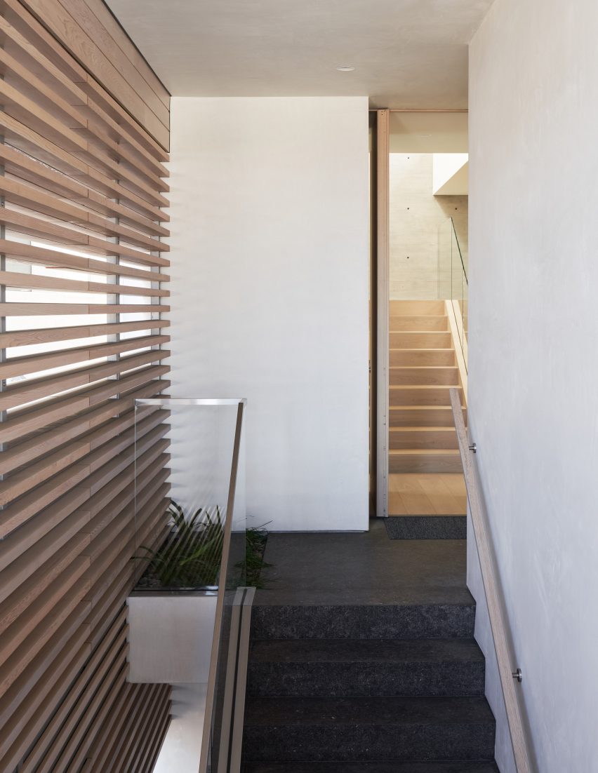 Top of a staircase with dark floors, white walls and timber-slatted siding