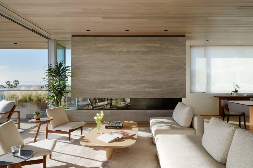 Living room with a white sofa, lounge chairs and a stone fireplace