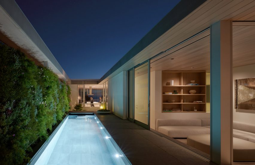 Long and narrow swimming pool at a Californian residence next to a green wall