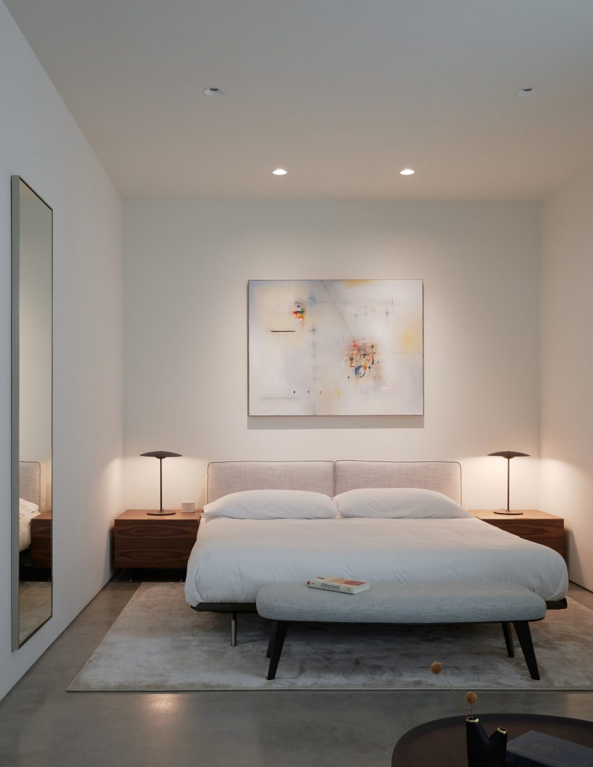 Bedroom with white walls, white bedding and dark wood bedside tables