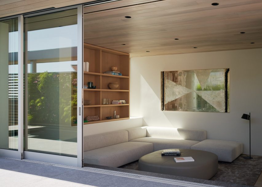 Outdoor terrace with sliding glass doors leading to a living room with a corner sofa