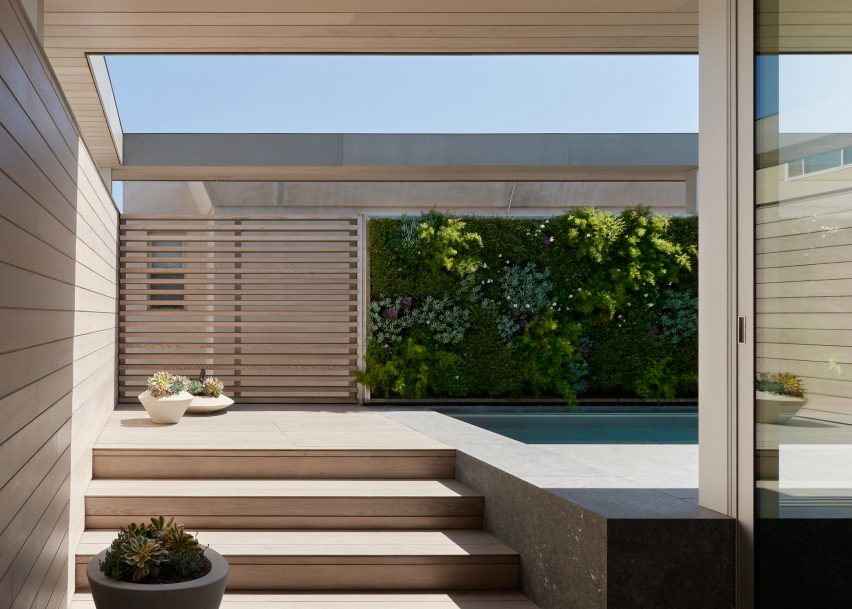 Steps leading to an outdoor swimming pool with a green wall